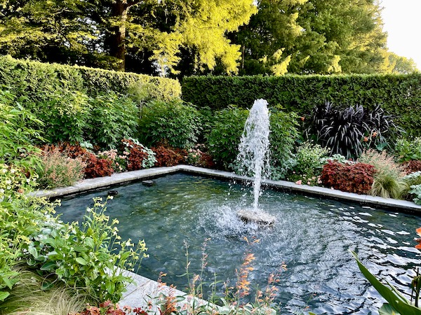 A rectangular reflecting pond with fountain surrounded by plants at Longwood Gardens Kennett Square PA