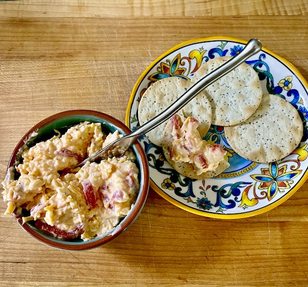 Small bowl filled with pimento cheese and a plate with crackers from new book Available Now Tasting Alabama