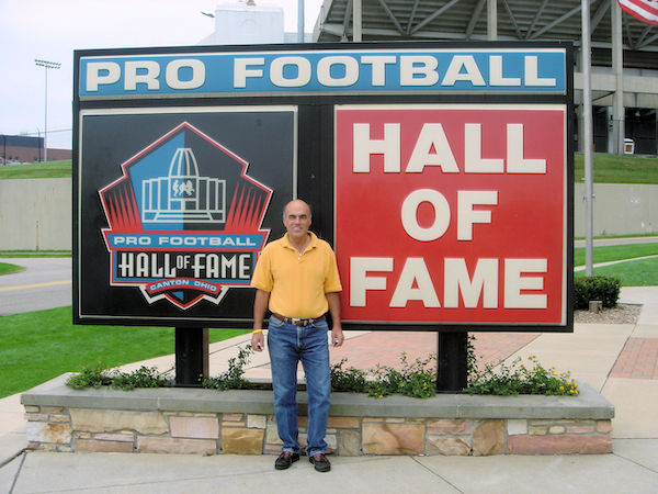 Steve standing in front of the sign for the Football Hall of Fame, Celebrating 3 Years as Full Time RVers!