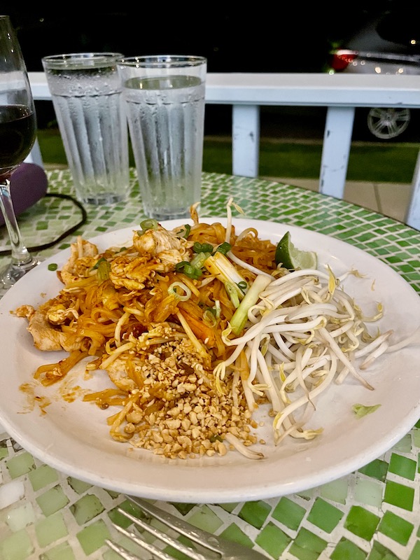 A plate of chicken pad Thai with noodles and bean sprouts.