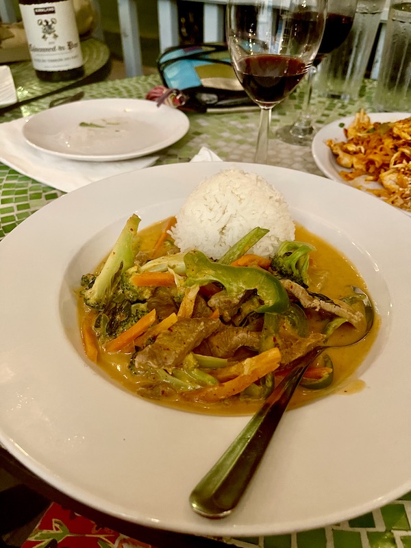 A plate topped with strips of beef, vegetables rice and sauce at a Thai restaurant in the big easy.