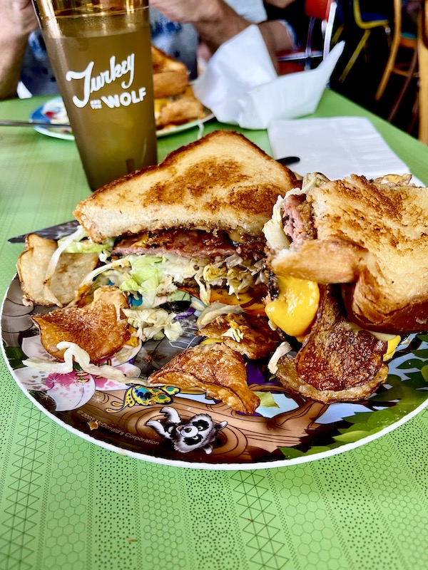 Sandwich cut in half showing fried bologna. chips and cheese at a place for Good Eats in the Big Easy
