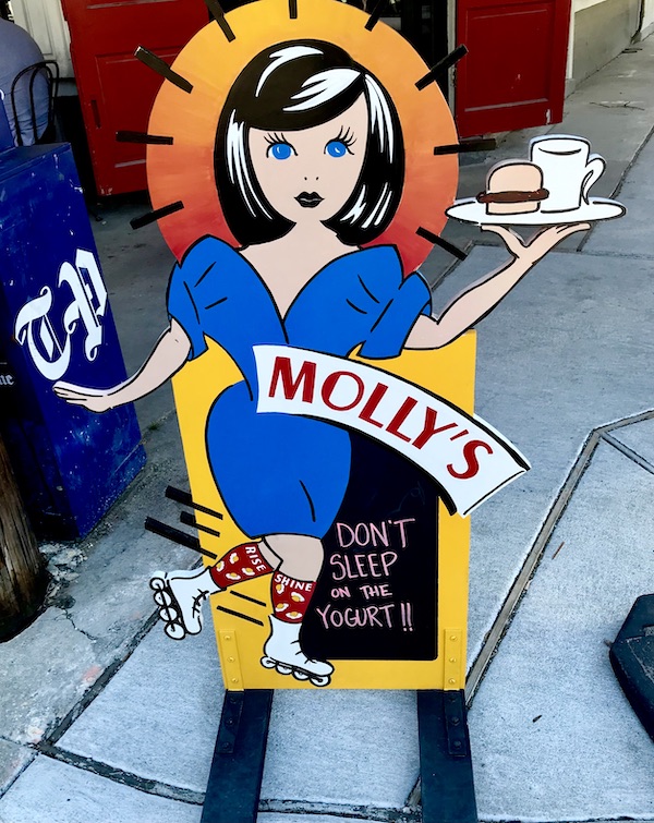 Colorful sandwich board sign of a girl with a plate of breakfast at a place for Good Eats in The Big Easy
