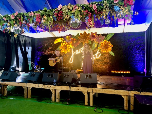 Colorfully decorated stage with man playing guitar and girl singing at New Orleans Jazz and Heritage Festival