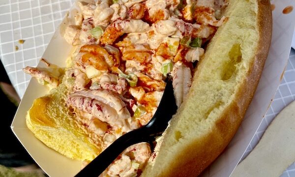 A long soft roll fill with crawfish salad and topped with a drizzle of hot sauce at New Orleans Jazz and Heritage Festival
