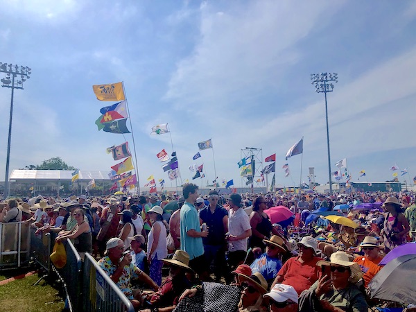 A sea of people and flags blowing in the wind at New Orleans Jazz and Heritage Festival