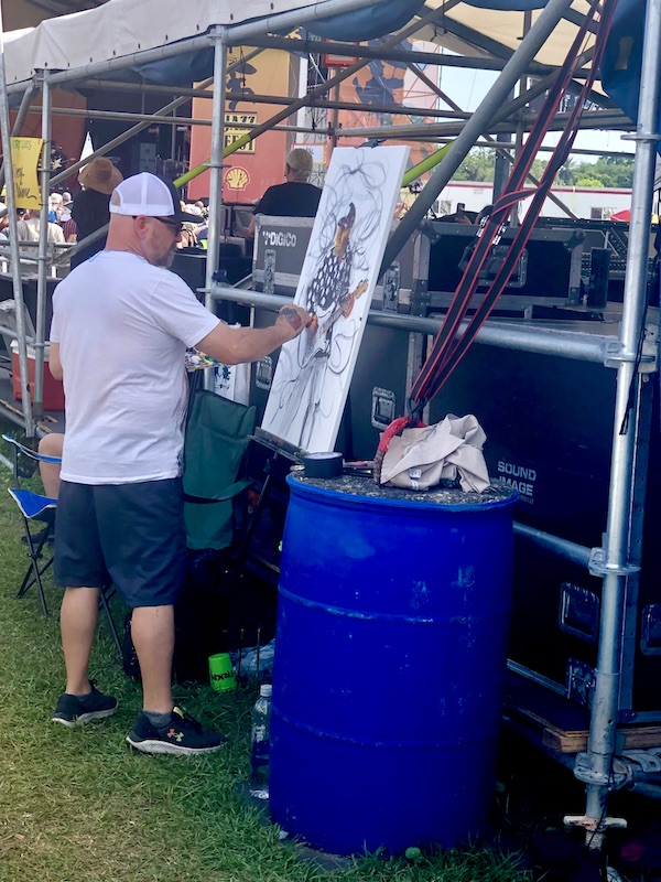 Artist adding color to the canvas at New Orleans Jazz and Heritage Festival