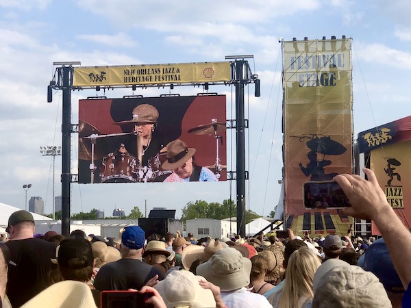 Female drummer and male guitar player perform on Jumbotron at New Orleans Jazz and Heritage Festival