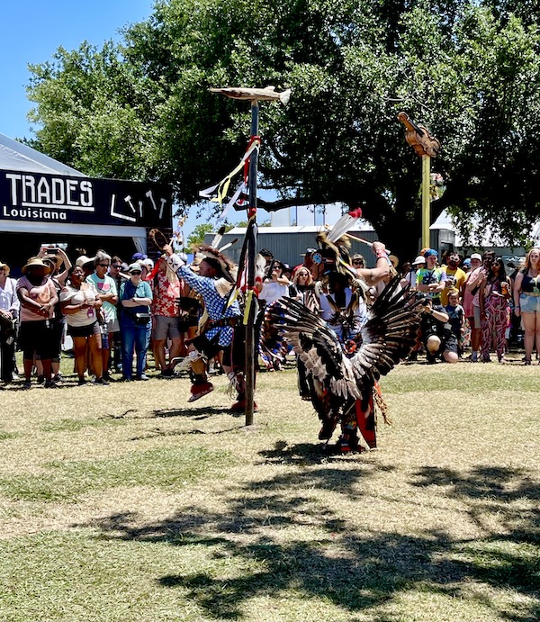 People watching a pair of Native Americans in full costume dancing at New Orleans Jazz and Heritage Festival