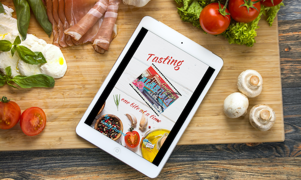 Tablet with cover of my book Available Now Tasting Alabama on a wood cutting board with produce and meat.