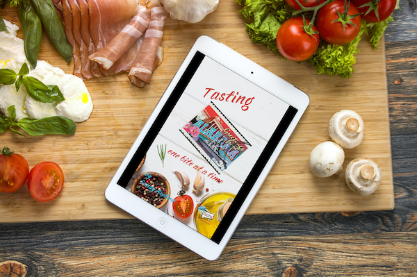 Tablet with cover of my book Available Now Tasting Alabama on a wood cutting board with produce and meat.