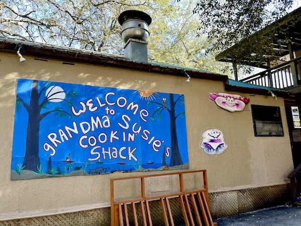 Restaurant building with blue sign welcoming you to Grandma Susie's Cookin Shack.