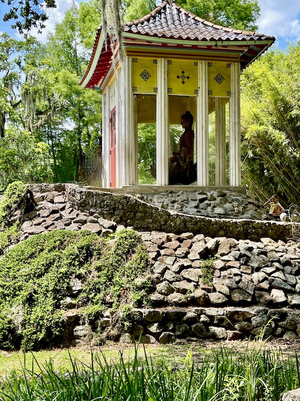 Pillared and glass enclosure protecting the buddha inside.