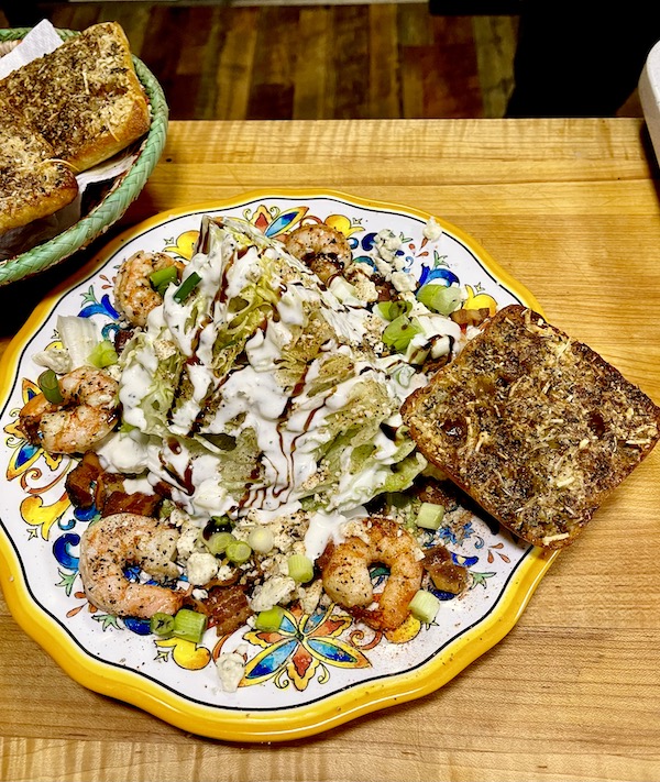 Plate of The Wedge Salad Cajun Style with shrimp and garlic bread