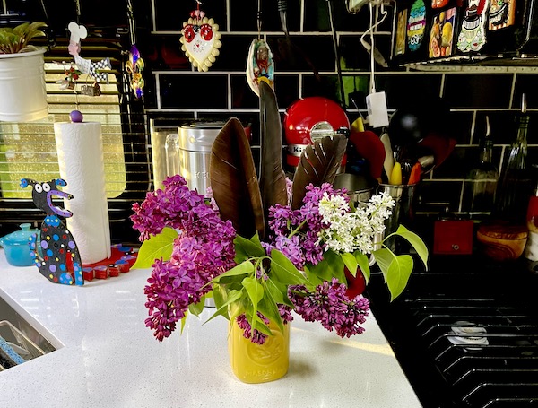 Yellow vase with lilacs on white countertop show how fresh flowers make an RV feel like home