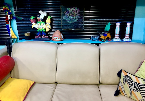 Beige sofa with teal shelf behind displaying art pieces as an example of How to Make Your RV Feel Like Home