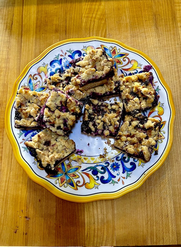 A colorful plate topped with several Luscious Blueberry Lemon Bars