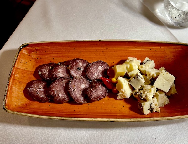 Orange rectangular plate topped with salami slices, tiny tear shaped peppers and chunks of cheese from Pasta And... Margate Florida