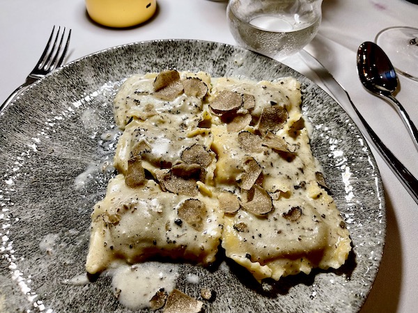 Gray plate topped with ravioli, creamy sauce and sliced black truffle from Pasta And... Margate Florida