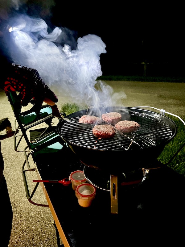 Weber Jumbo Joe Charcoal Grill with burgers cooking and smoke coming off the grill