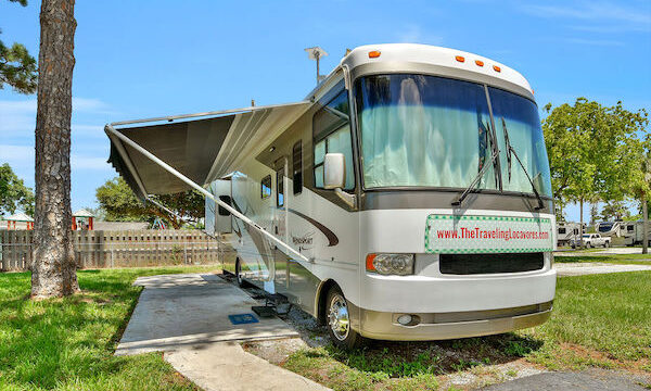 Class A motorcoach with awning out at an RV park.
