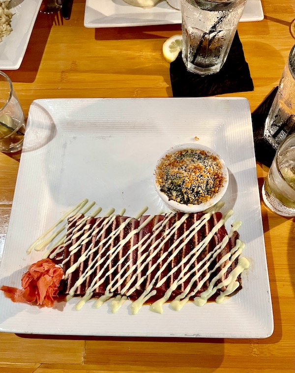 Bimini Twist Blackened Tuna with creamy wasabi drizzle, rosette of pickled ginger and a ramekin of spinach on a white square plate