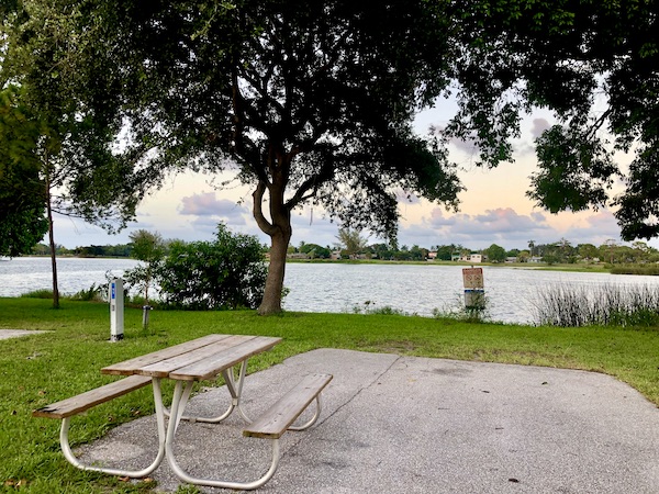 A clean RV campsite with picnic table by a lake showing we cleaned up before we left the site