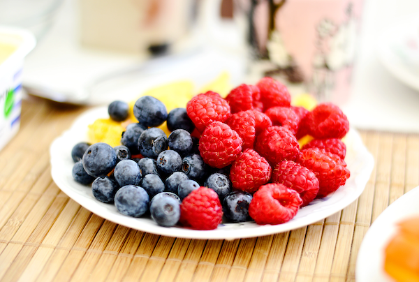 A plate full of fresh raspberries, pineapple and blueberries are one of 3 Healthy Snacks for any diet.