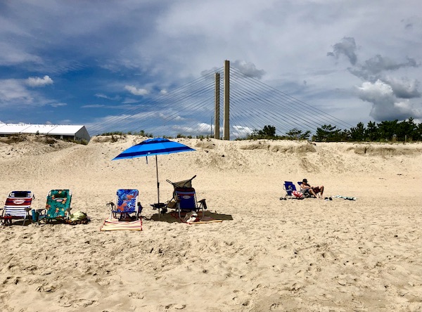 Beach with chairs and umbrellas, suspension bridge in the background