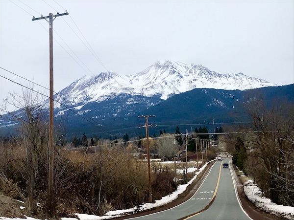 Lake with houseboats, highway and large snowcapped mountain in distance. Part of my 3 Years RVing Year 1 Recap