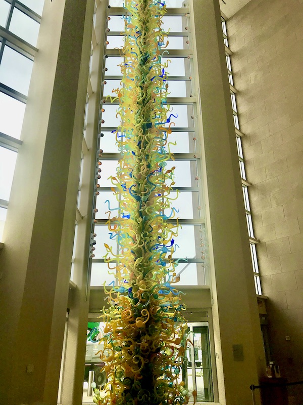 Inside an art museum with very tall glass sculpture in front of floor to ceiling windows