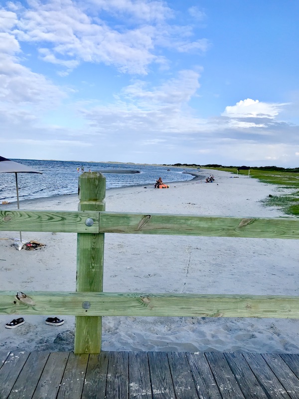 Beach and ocean seen through a wood fence to begin our 3 Years RVing Year 1 Recap