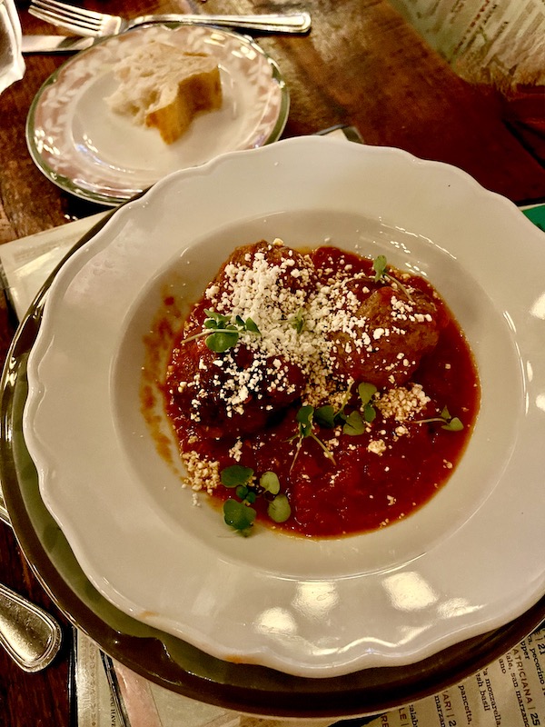 White shallow bowl filled with meatballs, red sauce and shredded cheese from Elisabetta's Ristorante Bar Pizzeria