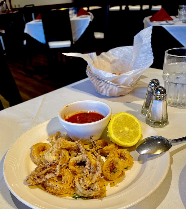 Plate of fried squid with red sauce in a cup and lemon half at Stresa Italian Restaurant WPB FL