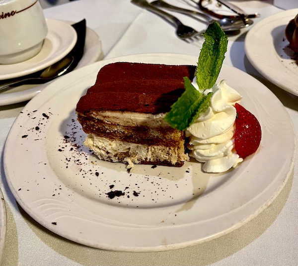 Slice of tiramisu on a plate garnished with chocolate shavings and whipped cream at Stresa Italian Restaurant WPB FL