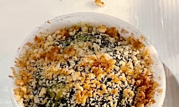 White serving bowl filled with Cheesy Spicy Spinach Maria on a white tablecloth.