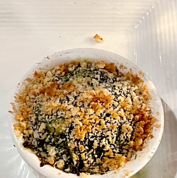 White serving bowl filled with Cheesy Spicy Spinach Maria on a white tablecloth.