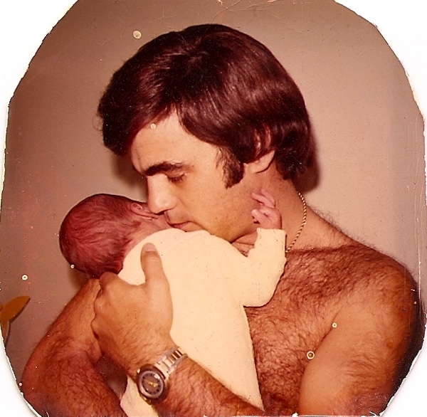 A very young Steve with no shirt holding our infant son.