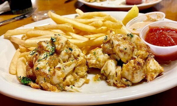 Pair of tall crabcakes and fries on a white oval platter at Eagle Grill and Oyster Bar Greenacres FL