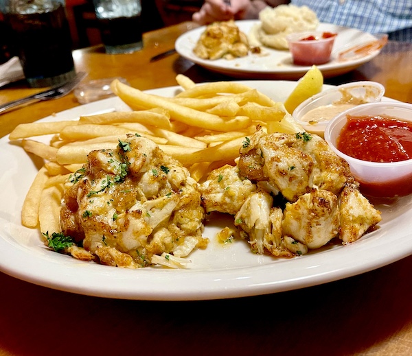 Pair of tall crabcakes and fries on a white oval platter at Eagle Grill and Oyster Bar Greenacres FL