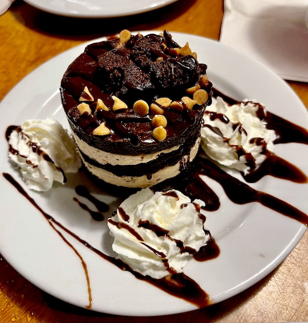 White plate topped with a chocolate and peanut butter mousse cake with fudge drizzle and whipped cream at Eagle Grill and Oyster Bar Greenacres FL