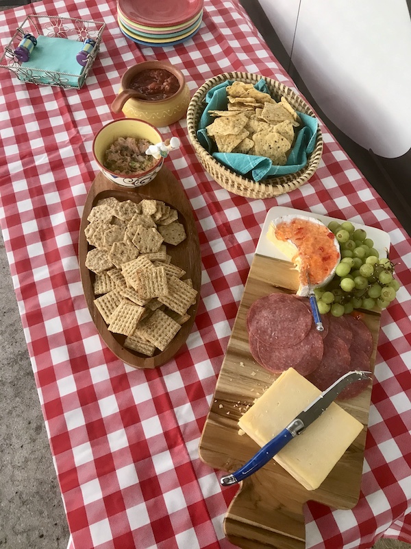 Picnic table with red and white cloth and lots of food.
