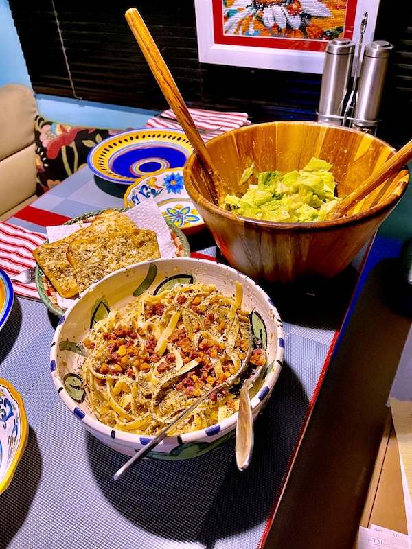 Our dinette set with wood salad bowl, bowl of pasta and basket of garlic bread to show how I Love to Feed People