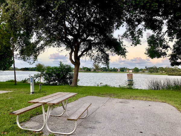 Empty RV site with view of lake and picnic table at John Prince Park Campground Lake Worth FL
