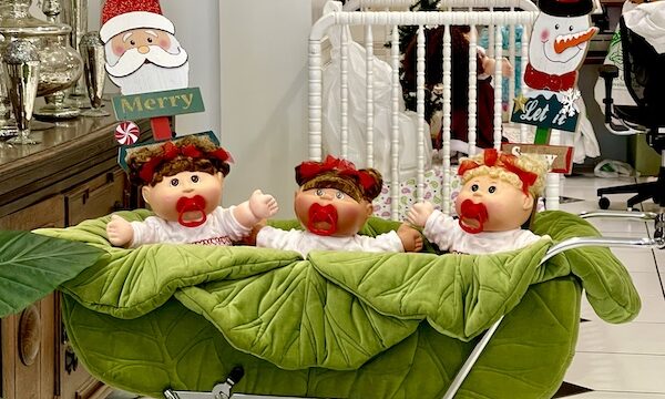 Stroller that looks like a cabbage holding 3 dolls with pacifiers at Cabbage Patch Babyland Cleveland GA
