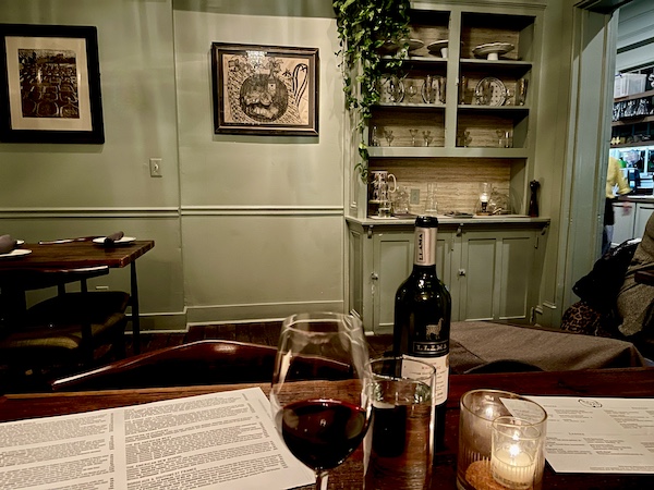 Five and Ten Athens GA dining room with sage green walls, shelves and table with wine.