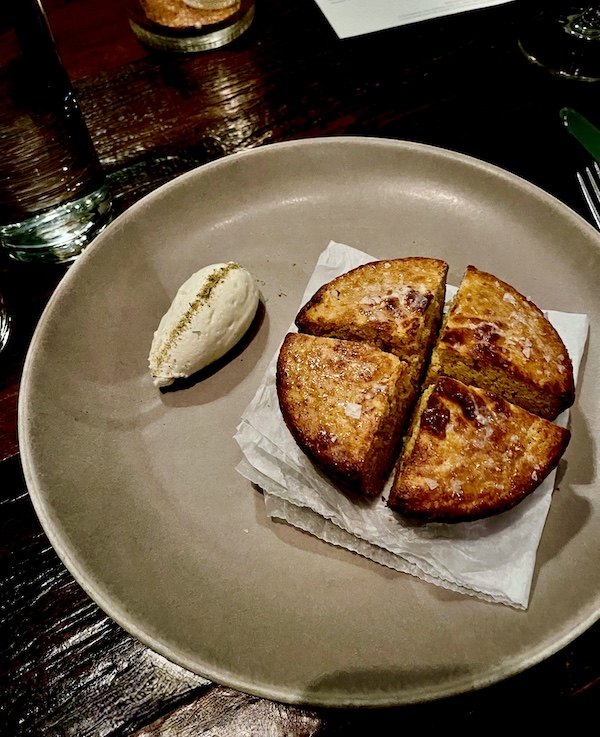 Beige plate with small round cornbread cut in 1/4s with butter at Five and Ten Athens GA