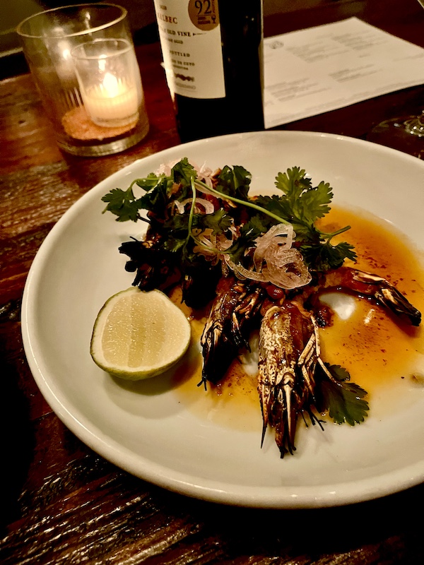Grilled head on shrimp on a white plate with lime half, herbs and sauce at Five and Ten Athens GA