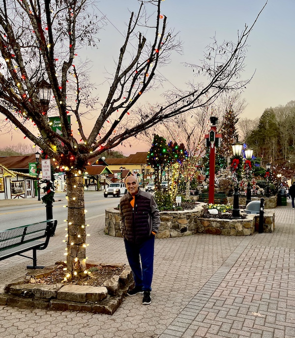 Steve standing by a lit tree as the sun sets during Holiday Season in Helen Georgia
