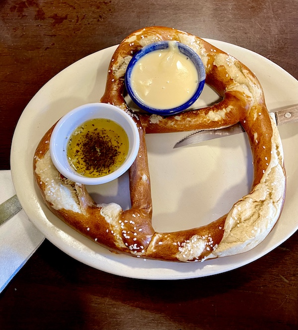 The Heidelberg Restaurant Helen GA giant Bavarian pretzel on a white plate with 2 dipping sauces.